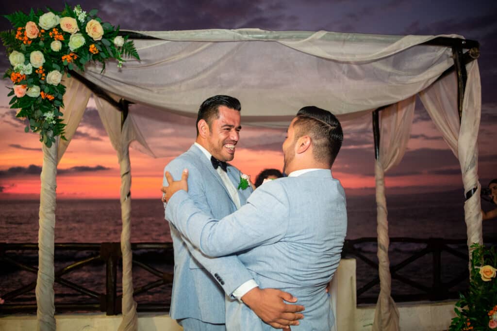 Couple smiling and embracing at a wedding ceremony.