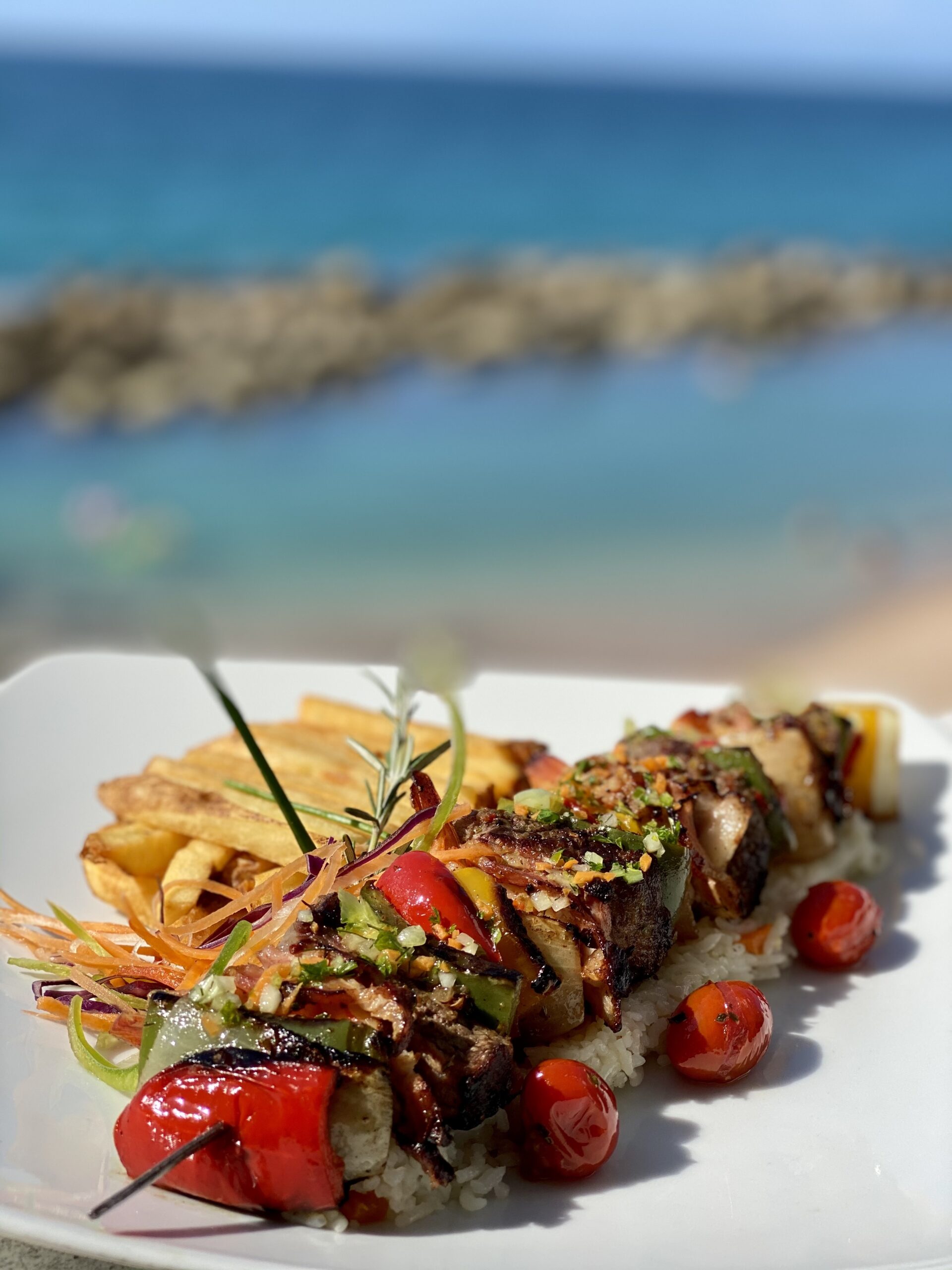 Grilled skewers with vegetables served by the ocean.