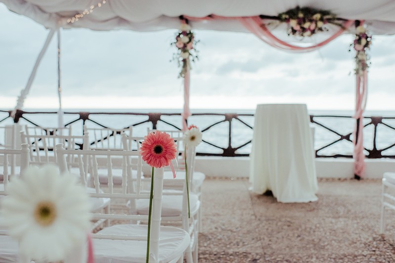 Focus on the pink flowers with the alter and ocean in the background.