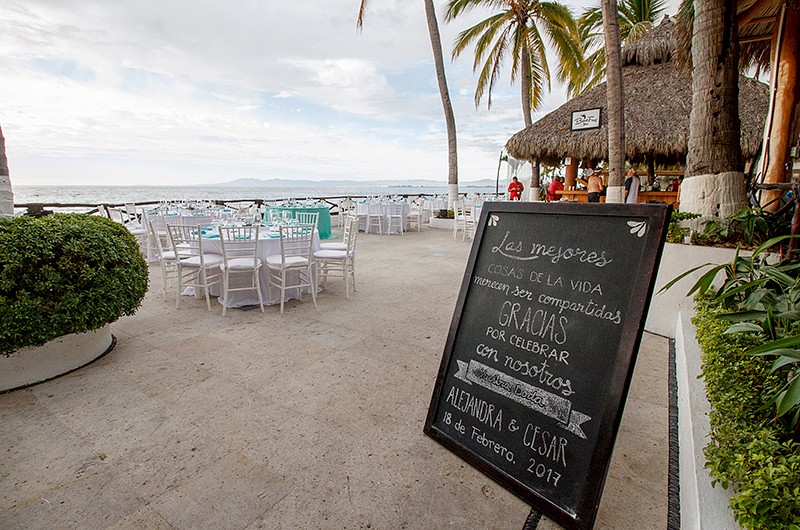 Entrance to an outdoor wedding reception focusing on a sign greeting guests in Spanish.