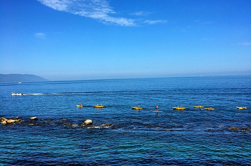 View of ocean with a class of kayakers and one paddle boarder.