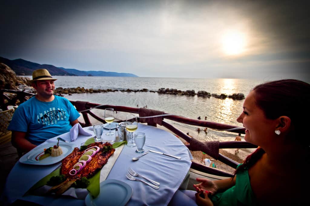 Couple enjoying a seaside dinner during sunset.