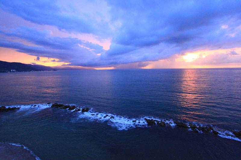 Sunset with warm purple and blue tones and the calm ocean.