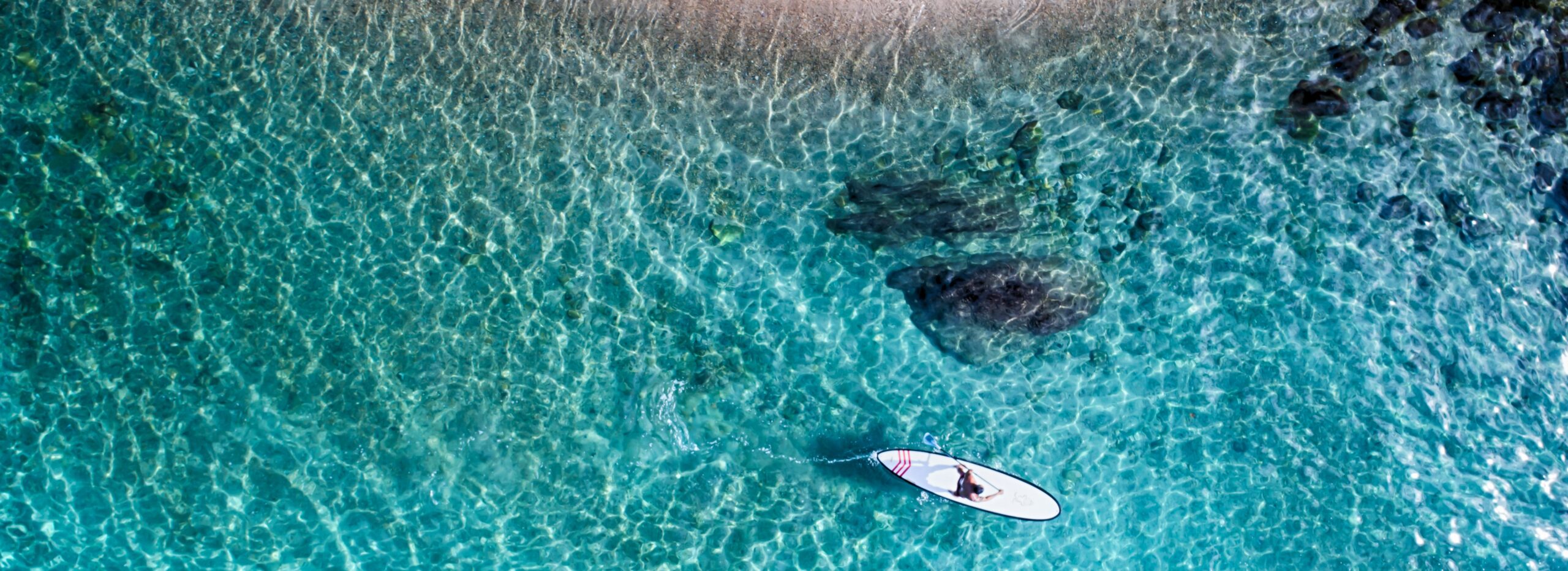 Paddleboarder gliding over clear turquoise water.