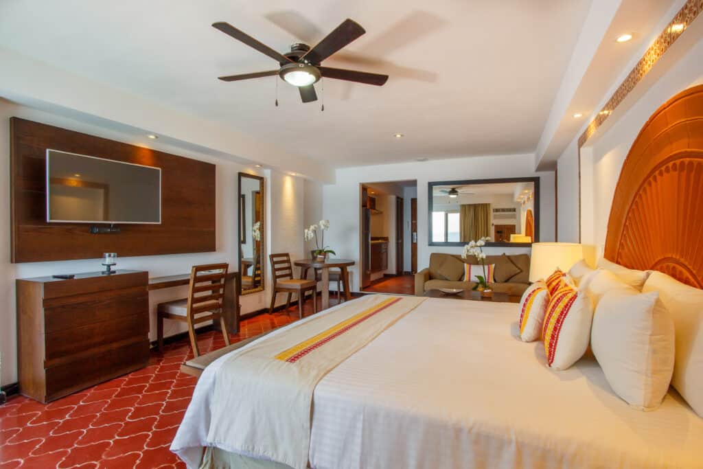 Spacious hotel room with modern decor and ceiling fan.