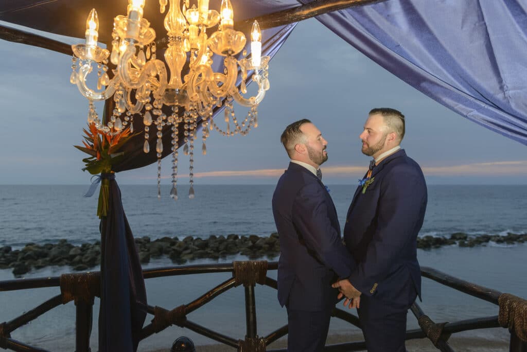 Couple holding hands and smiling in a romantic sea side setting.