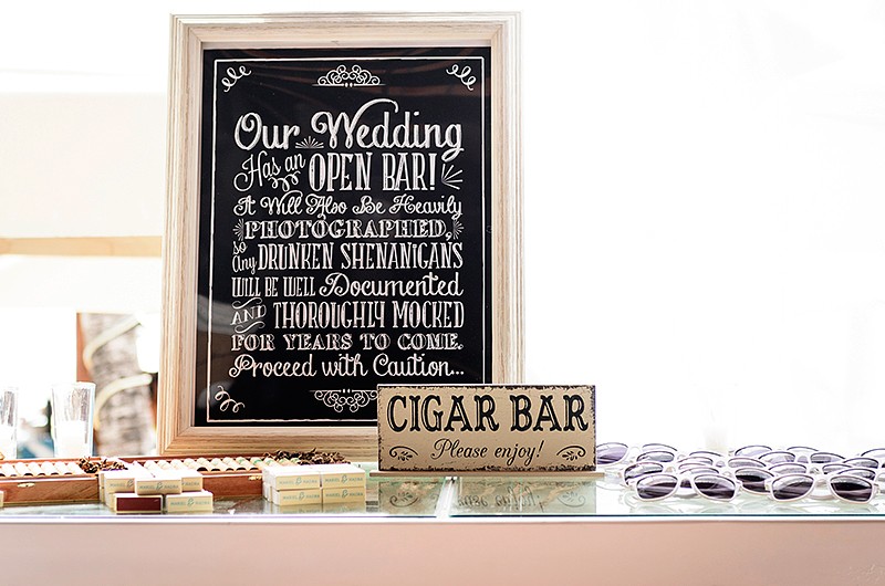 A wedding table with a photo of a wedding sign that says "Our Wedding Has An Open Bar! It Will Also Be Heavily Photographed.