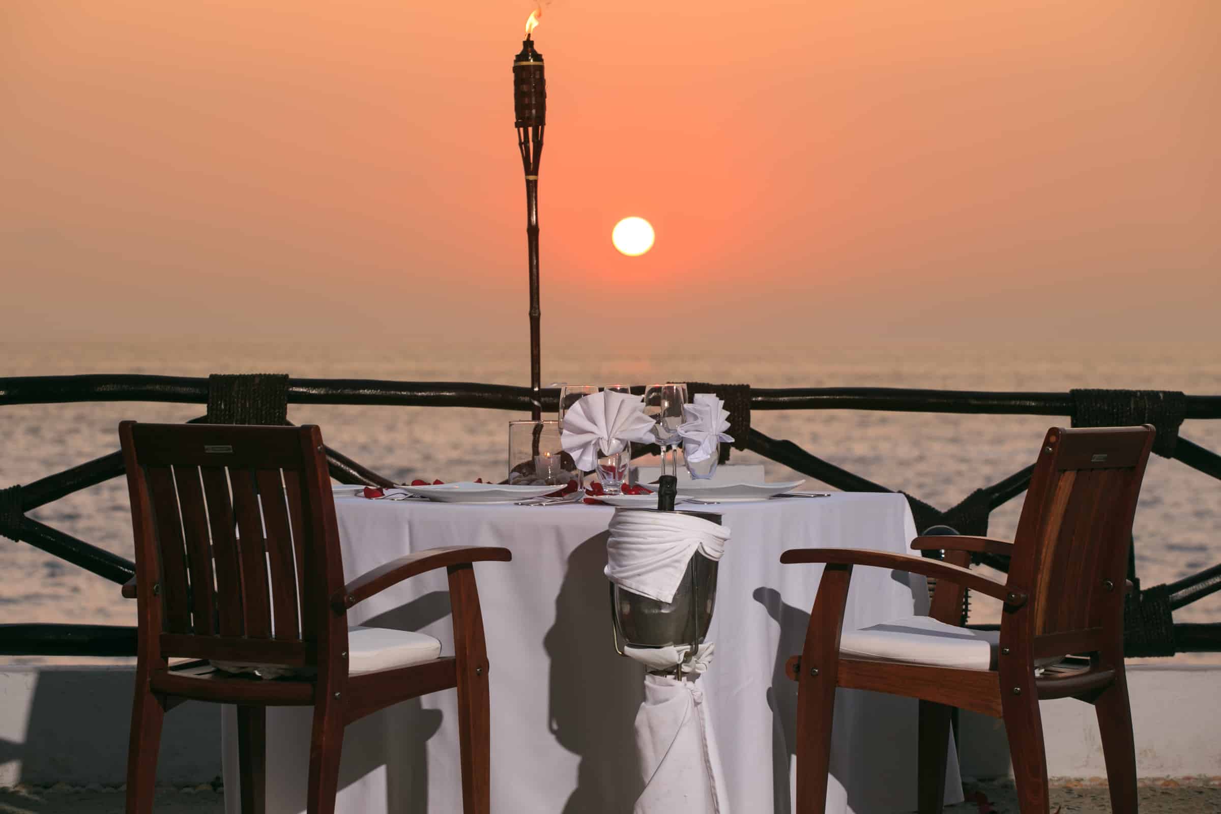 Restaurant table set for a sunset meal by the sea.