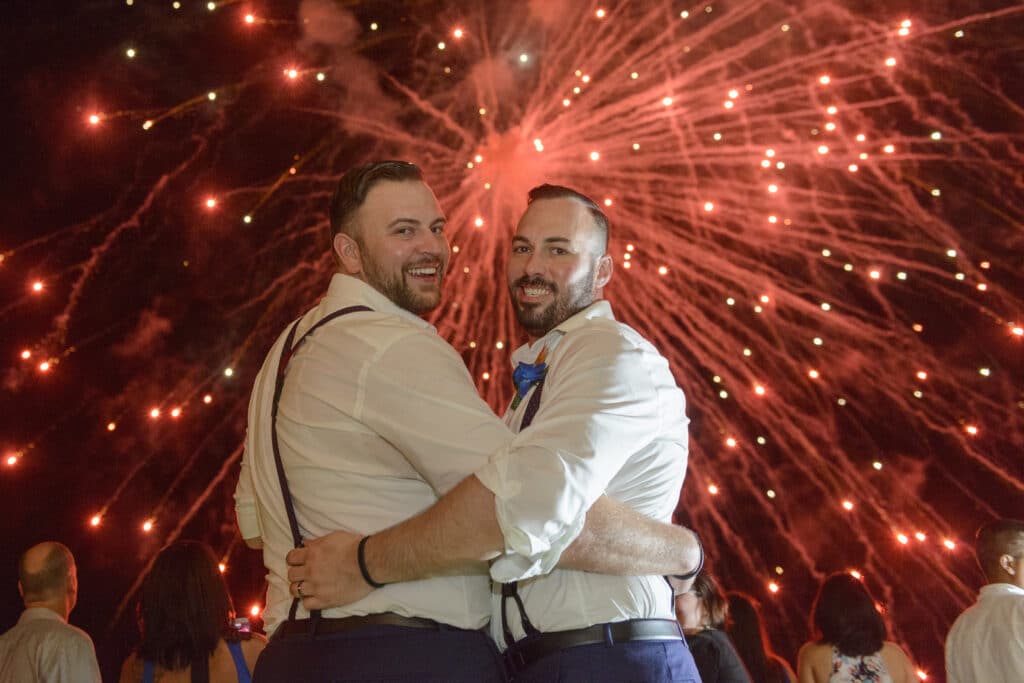 Couple smiling with fireworks in the background.